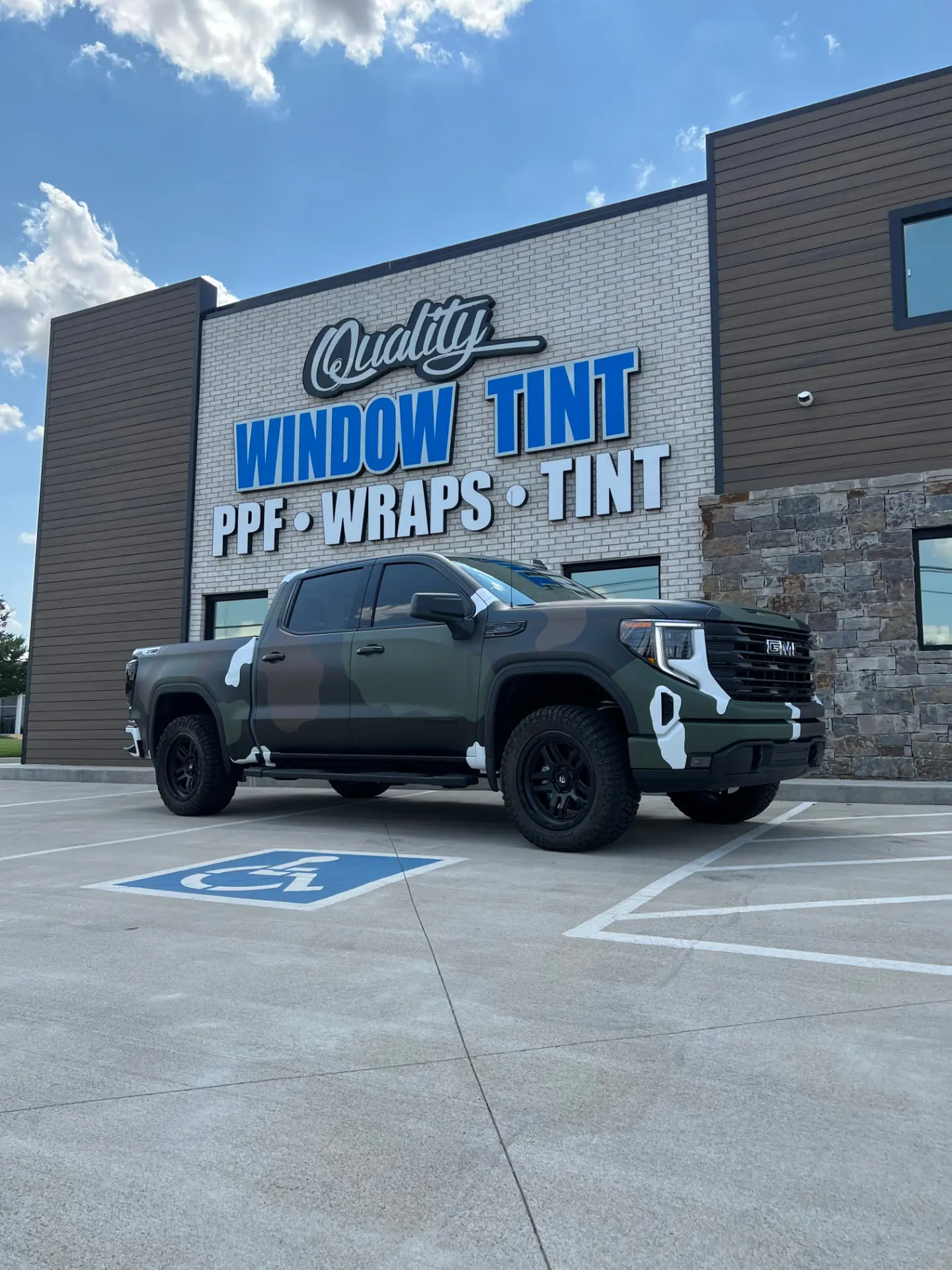 Green GMC Sierra truck with a custom vinyl wrap parked in front of the Quality Window Tint shop in Edmond